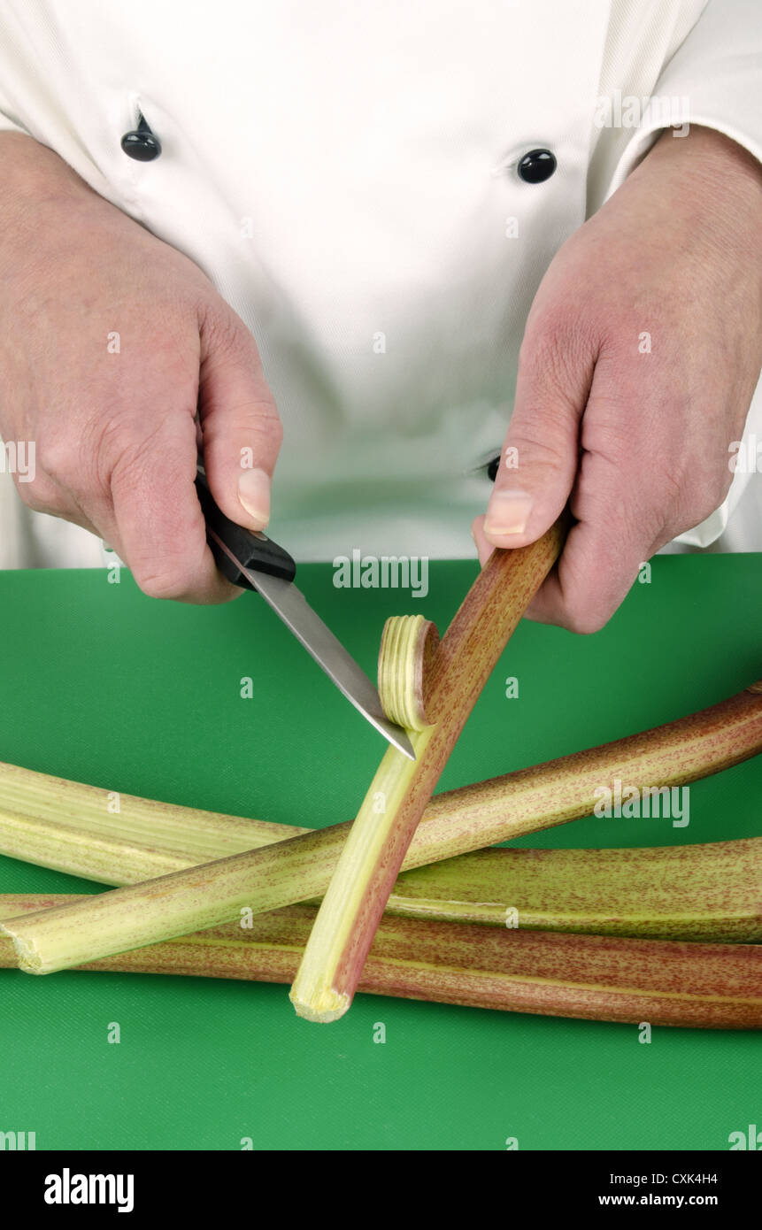 Femme chef de préparer certains rhubarbe avec un couteau de cuisine Banque D'Images