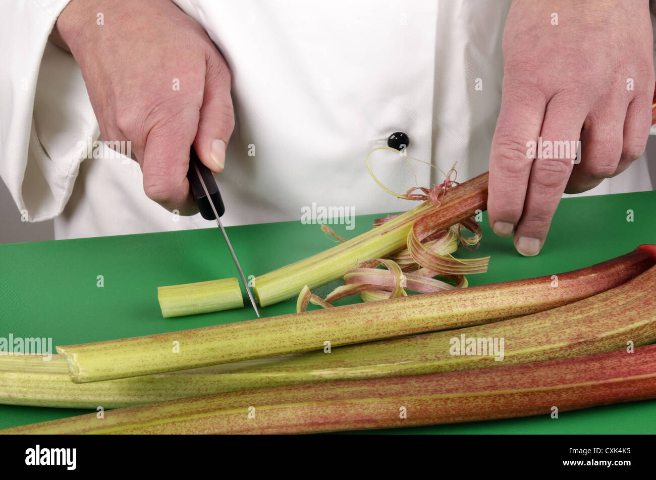 Femme chef de préparer certains rhubarbe avec un couteau de cuisine Banque D'Images