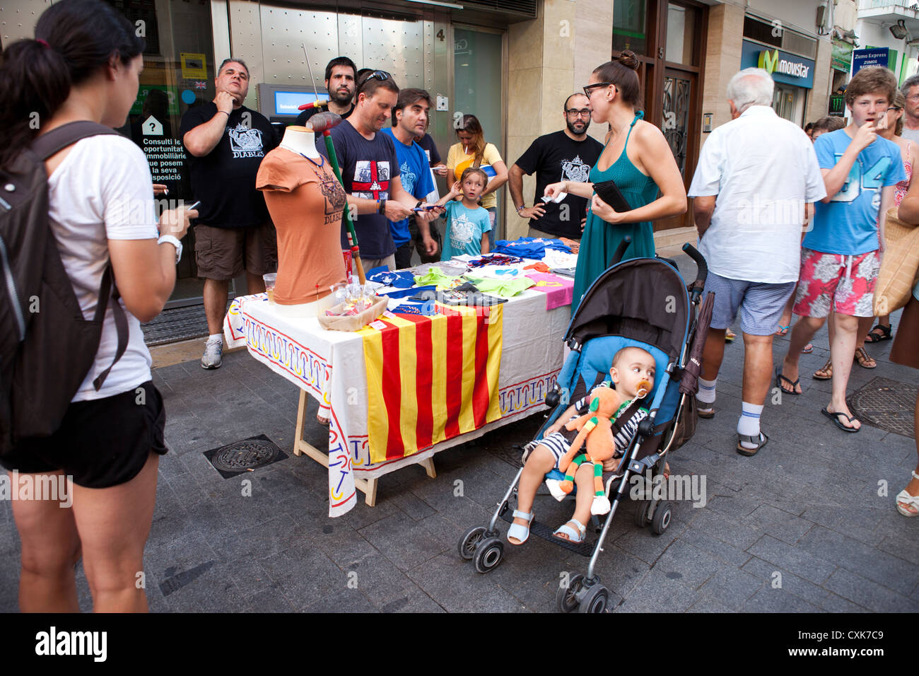 Les touristes et les habitants d'arrêt check-out les offrandes d'un vendeur de rue à Sitges, Espagne. Banque D'Images