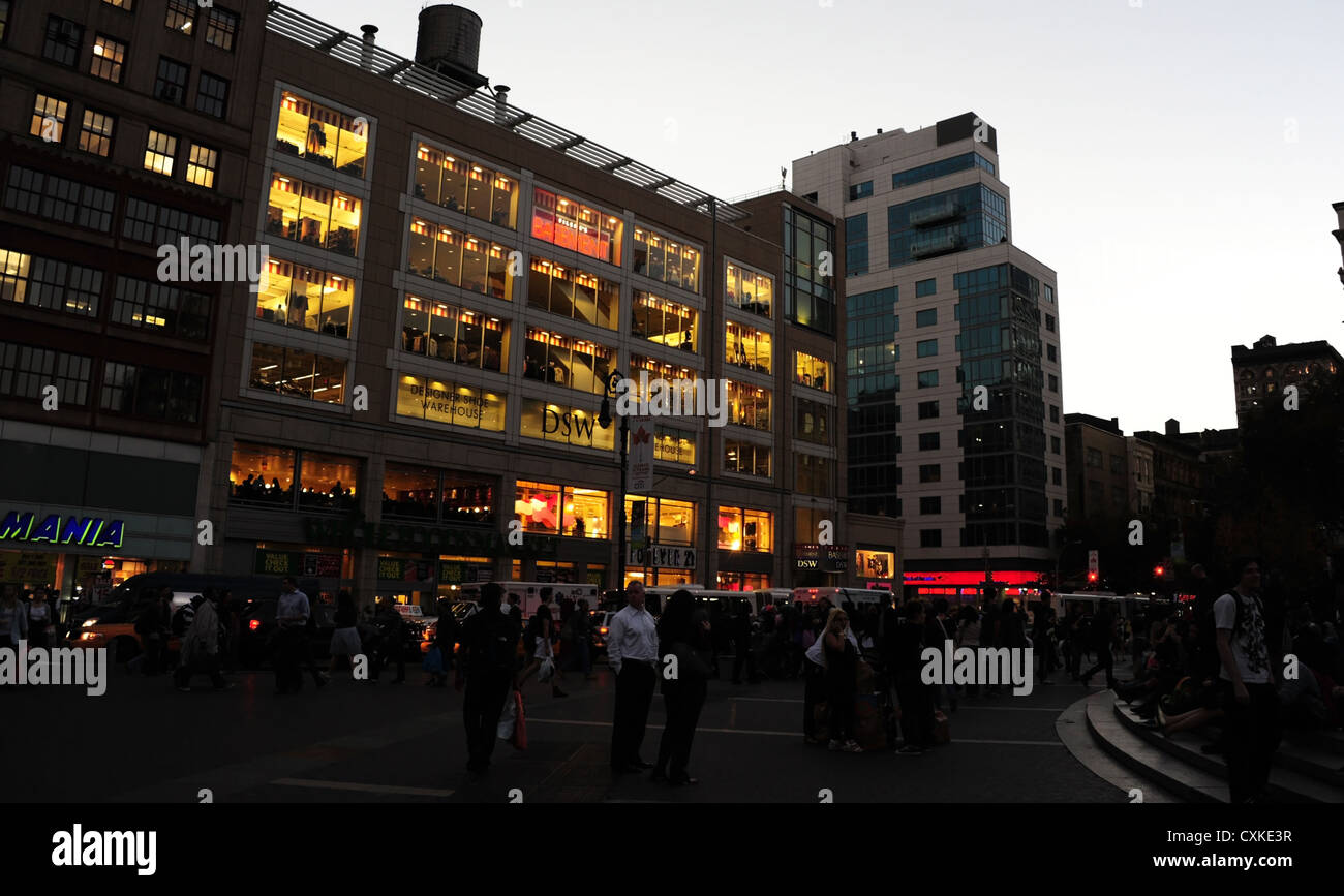 Vue Twilight, de Union Square à l'Est, les gens qui se plaza trottoir, l'éclairage électrique des bâtiments, East 14th Street, New York Banque D'Images