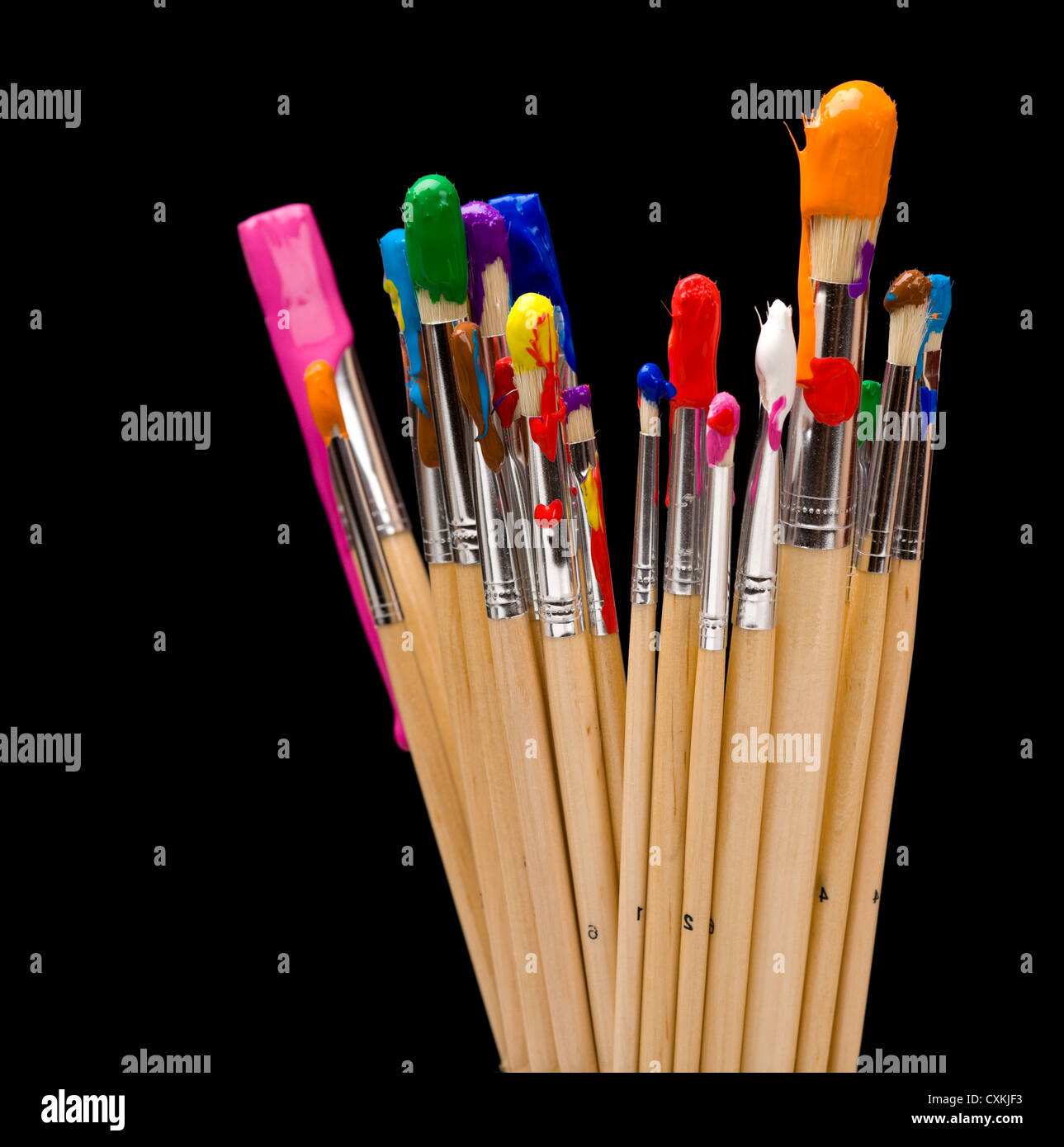 Un groupe de pinceaux de plusieurs couleurs sur un fond noir Banque D'Images