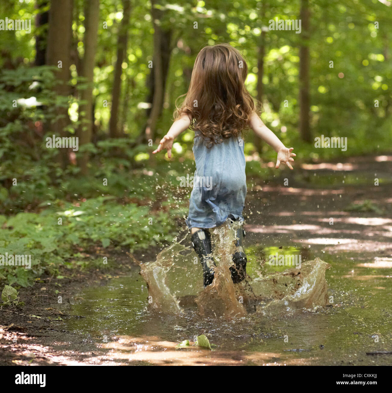 Little girl jumping in puddle Banque D'Images