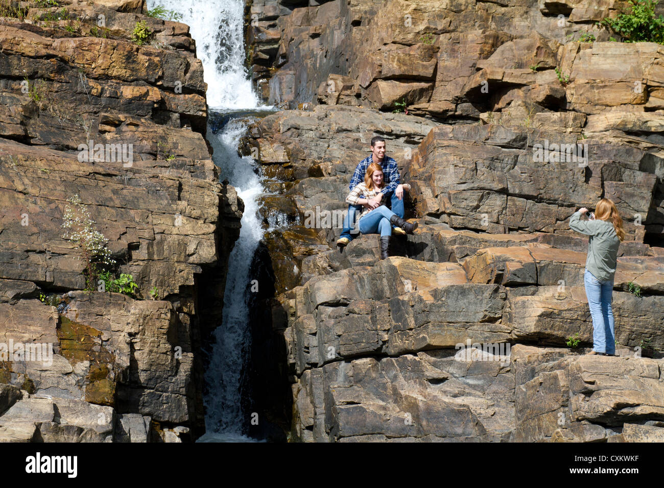 Les jeunes white Caucasian couple homme et femme photographiée sur les rochers à côté d'une cascade. Banque D'Images