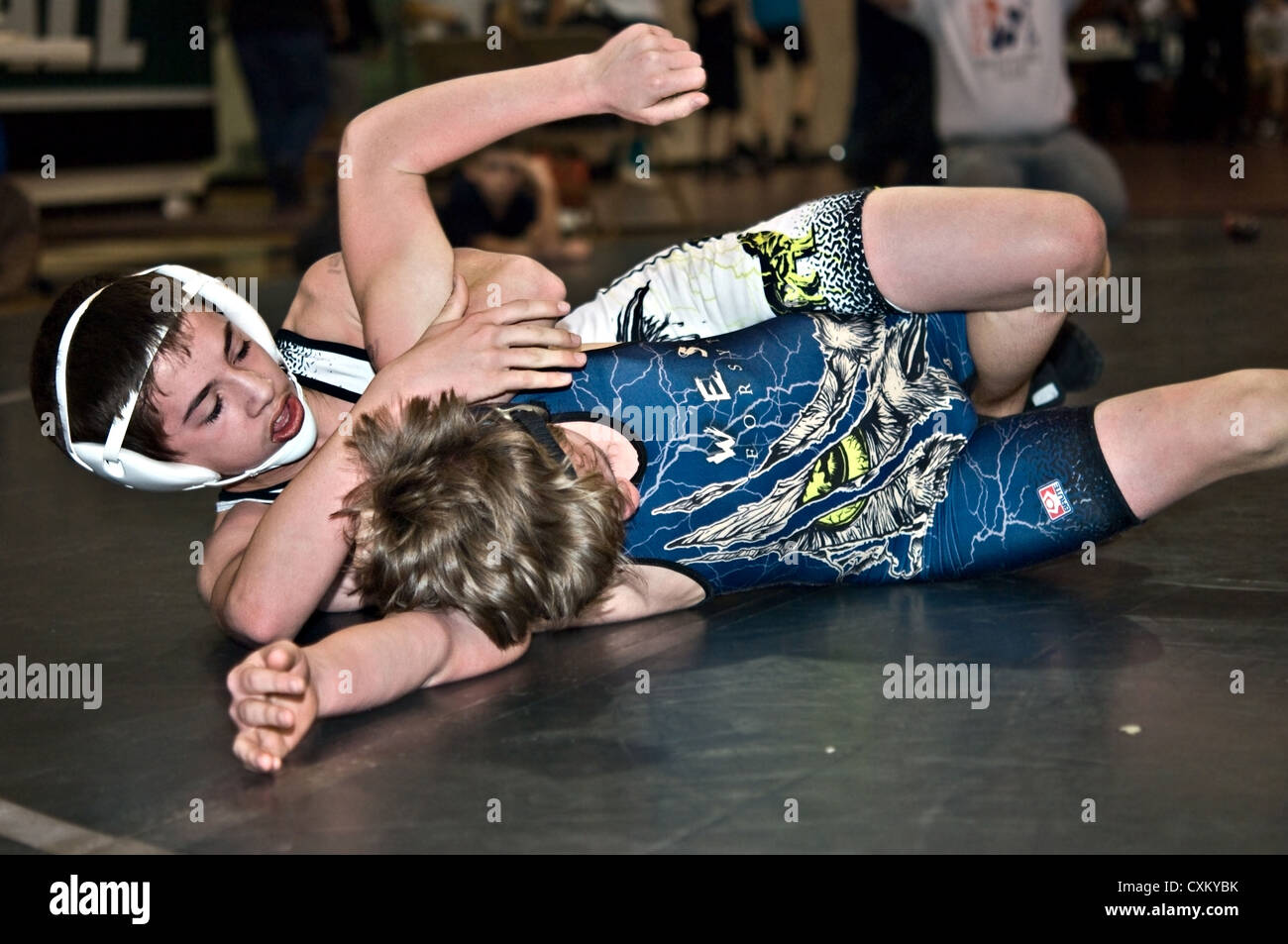 Deux jeunes garçons qui luttent sur le plancher pendant un match de lutte. Banque D'Images