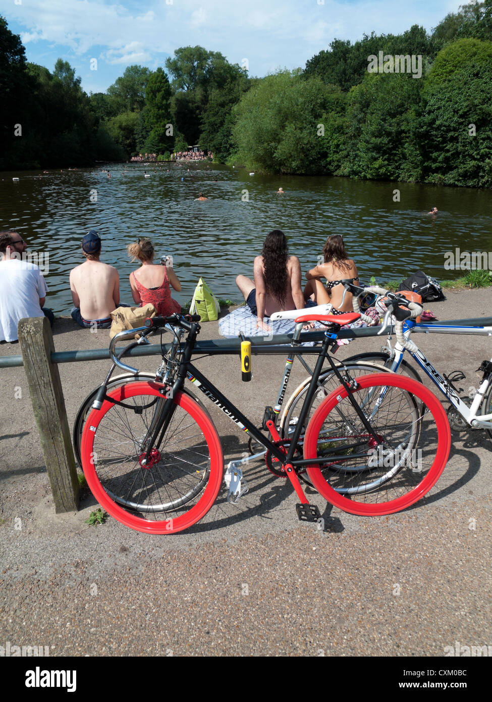 Baigneurs personnes et vélos vélos à l'étang de baignade mixte Hampstead Heath lors d'une journée chaude en été Nord de Londres Royaume-Uni Grande-Bretagne KATHY DEWITT Banque D'Images