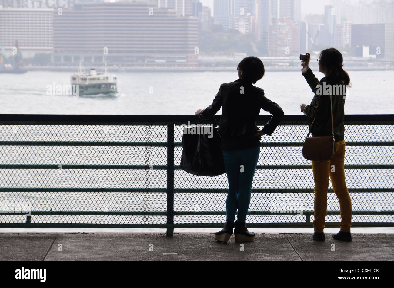 Deux jeunes filles de prendre des photos de Victoria Harbour et le Star Ferry, Hong Kong Banque D'Images