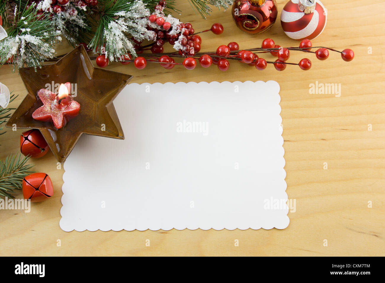 Carte de Noël blanche avec étoile rouge flottante bougie, Rusty star, grelots, Holly et copyspace Banque D'Images