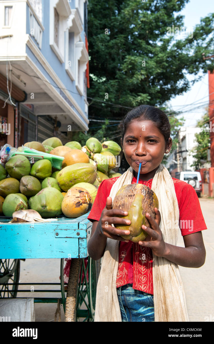 Happy young Indian street girl drinking eau de noix de coco de la noix de coco dans une rue en Inde Banque D'Images