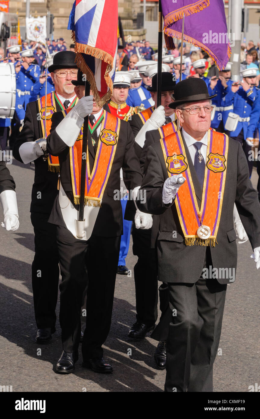 Un certain nombre des orangistes, vêtu du costume traditionnel 'Orange' ceinture chapeau melon et marcher sur une route pendant une parade de l'ordre d'Orange Banque D'Images