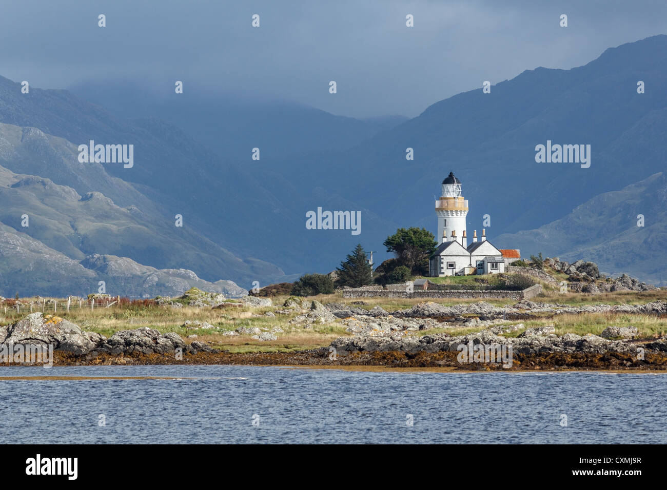 Vieux phare sur Isle Ornsay sur Skye avec des montagnes sur le continent écossais au-delà. Banque D'Images