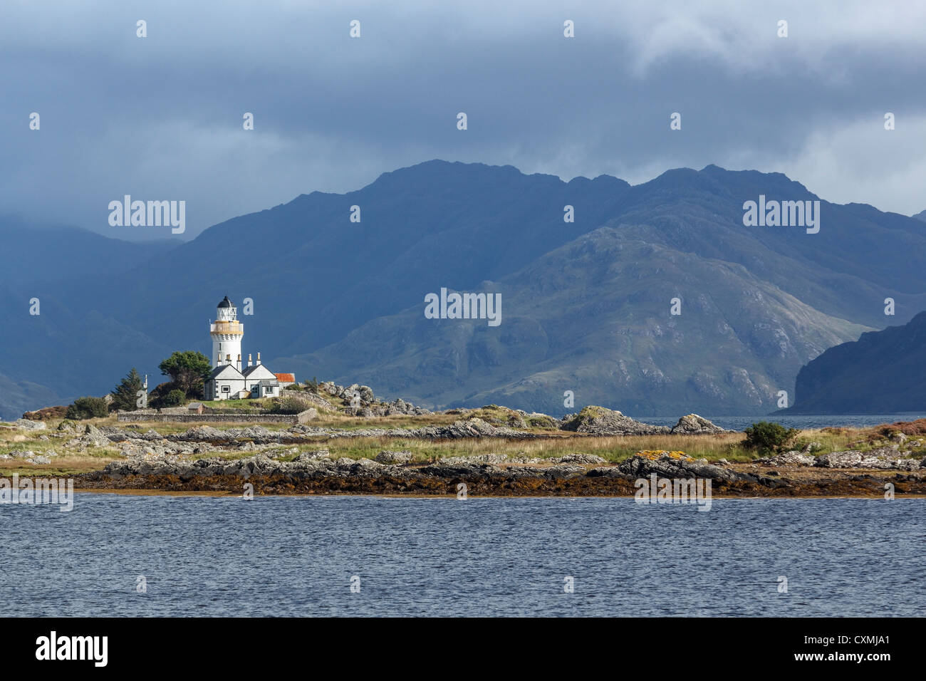 Vieux phare sur Isle Ornsay sur Skye avec des montagnes sur le continent écossais au-delà. Banque D'Images