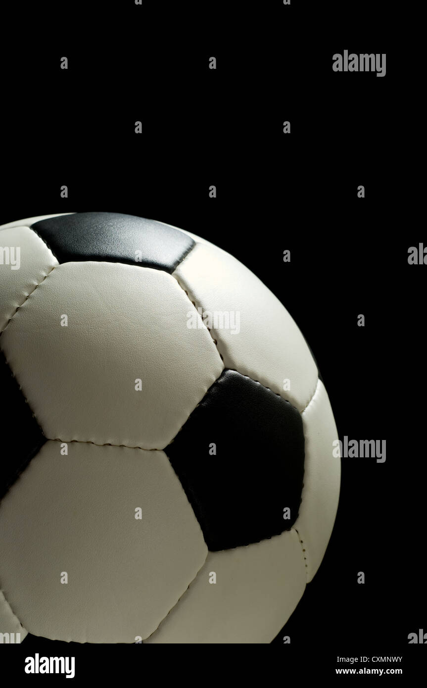 Ballon de football américain ou européen de football sur fond noir allumé par le haut avec copie espace au-dessus et à droite de la balle Banque D'Images