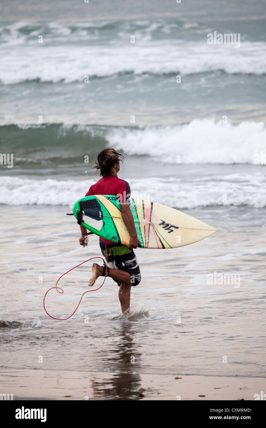 Surfer sur la plage de Kuta à Bali Banque D'Images