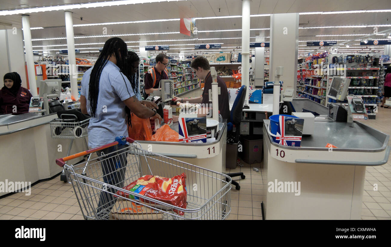 Chariot de chargement et payer les consommateurs à la caisse du shopping dans un supermarché Sainsbury's Walthamstow London England UK KATHY DEWITT Banque D'Images