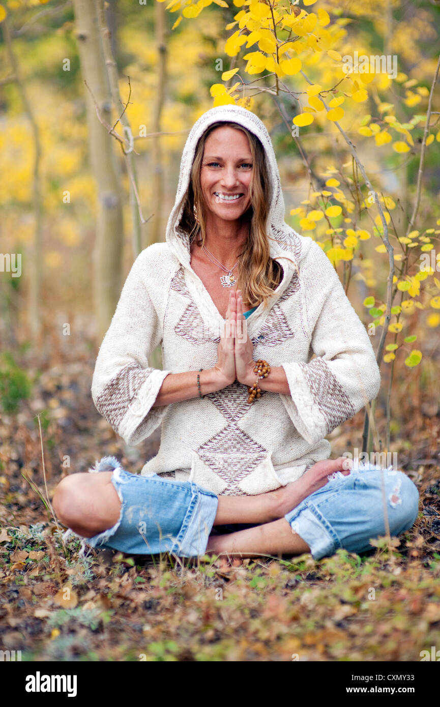 Femme à l'extérieur dans la saison d'automne smling dans une méditation yoga pose. Banque D'Images