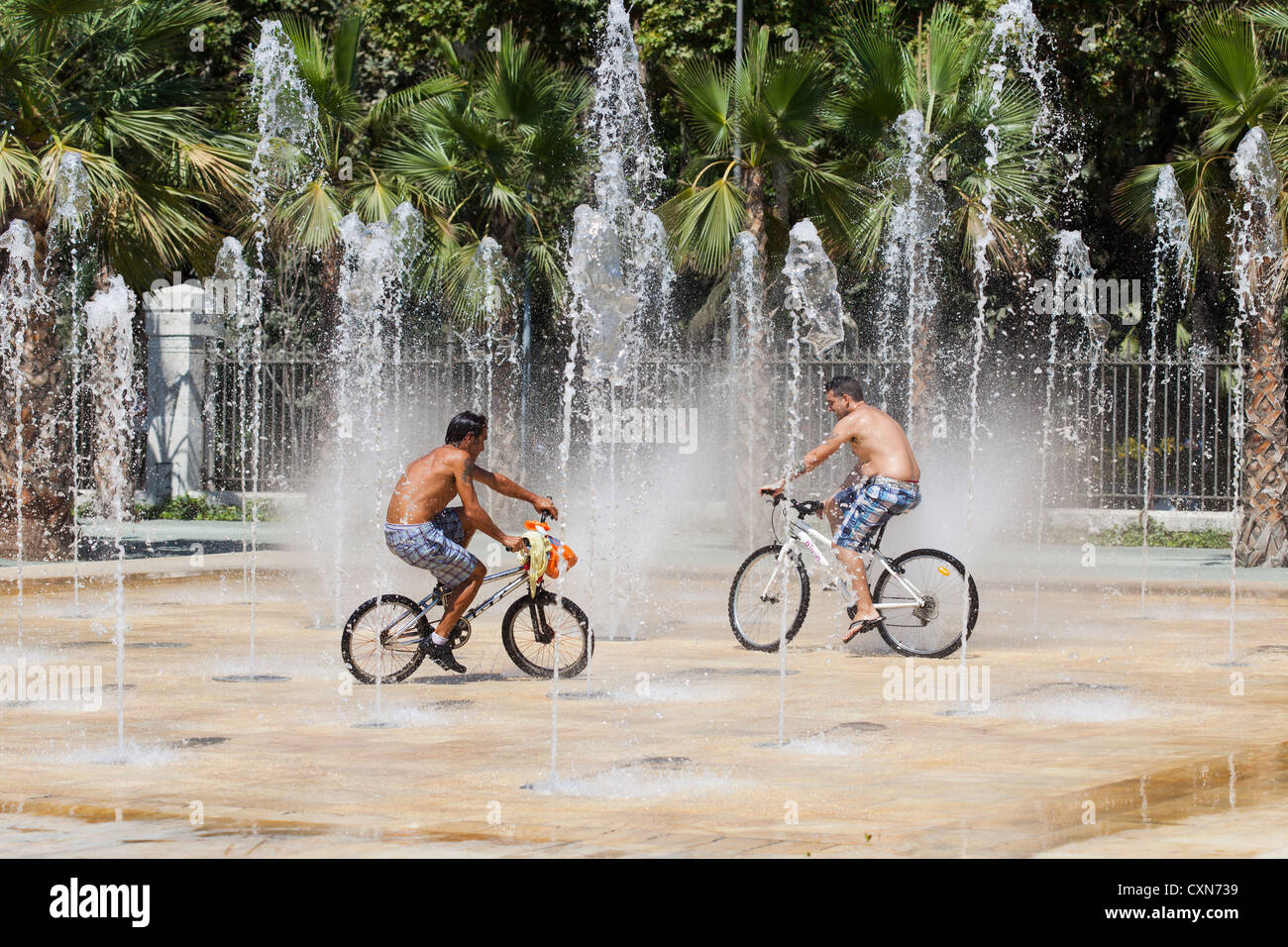 Les jeunes hommes vélo vélos dans des fontaines d'eau. Le port de Malaga en Espagne. Banque D'Images