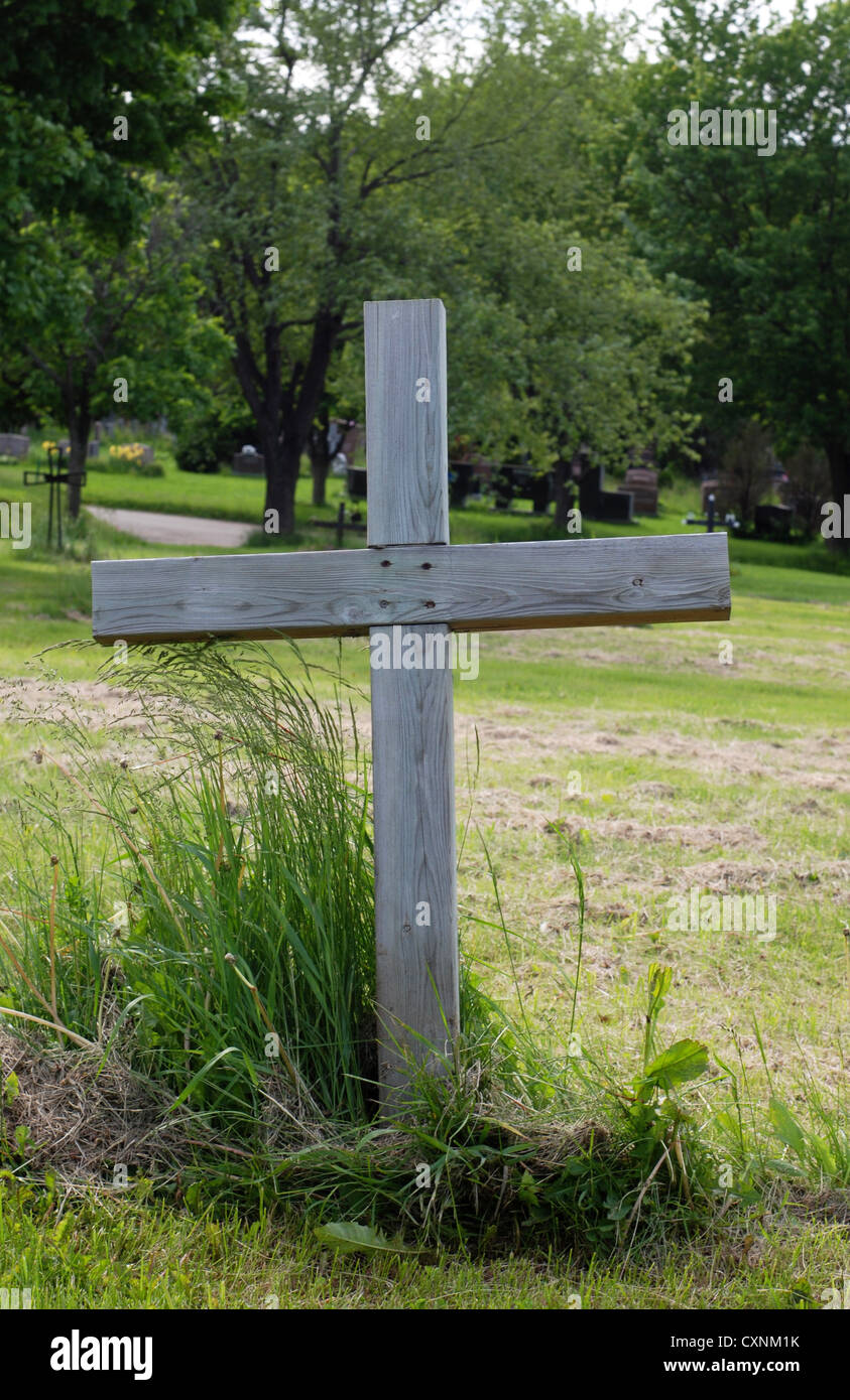 Croix de bois simple et unique à une sépulture dans un cimetière en plein air. Banque D'Images