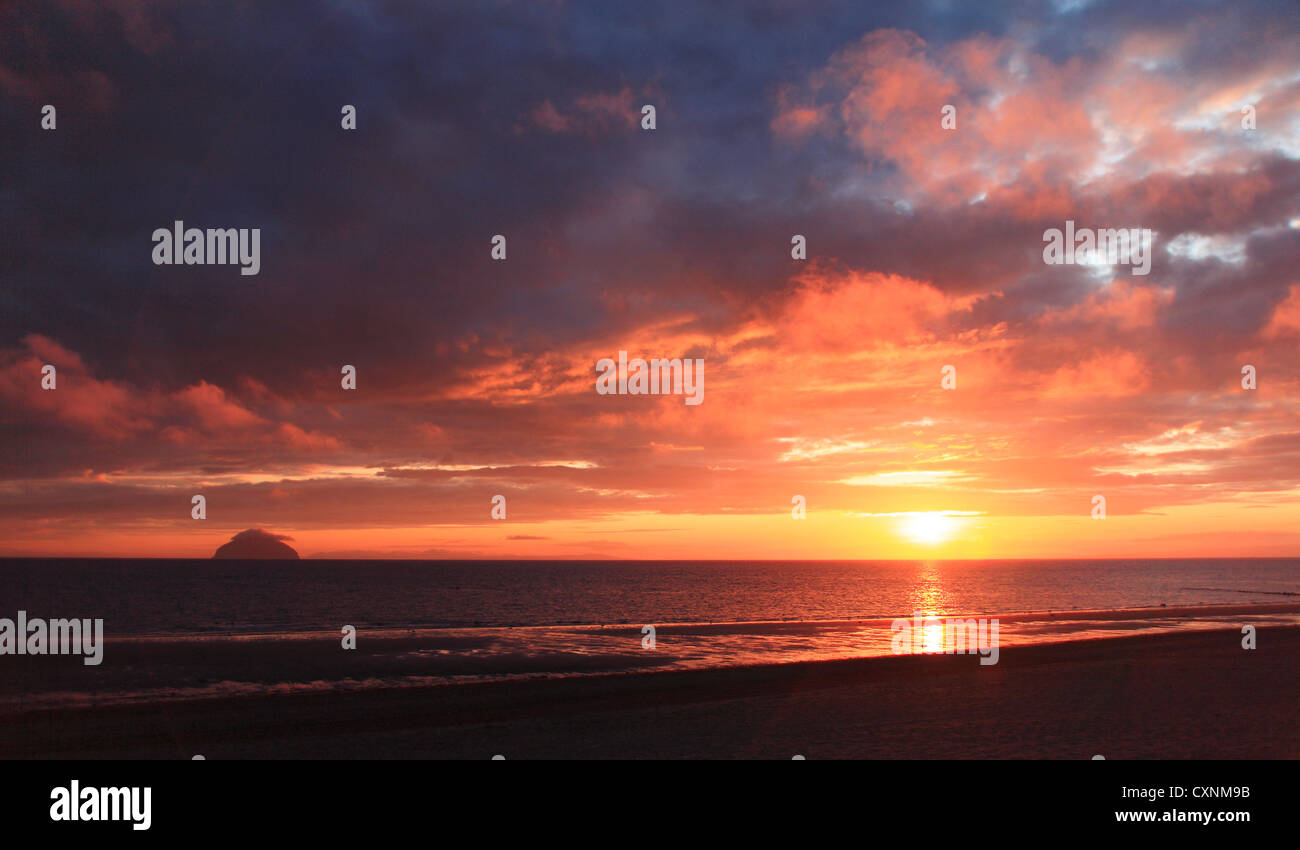 Ailsa Craig, au coucher du soleil vue à travers l'eau profonde - orange rouge ciel. Banque D'Images