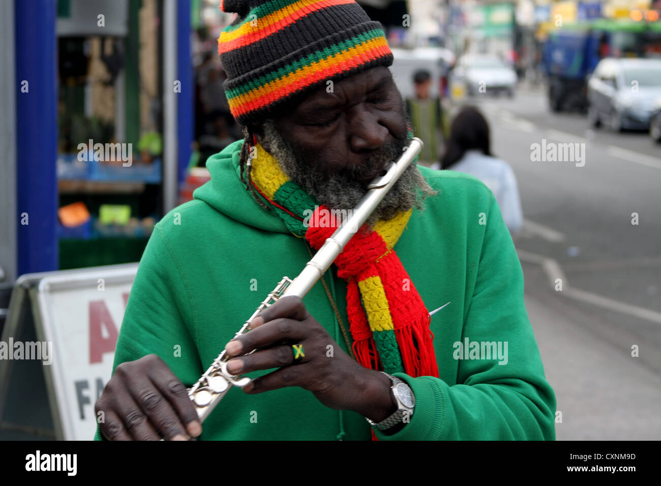 Joueur de flûte à l'flutewise à Londres, dans des couleurs du drapeau jamaïcain rastafari port anneau de doigt, trois petits oiseaux. Banque D'Images