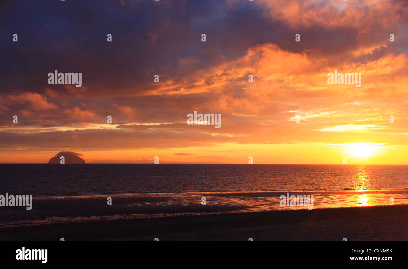 Ailsa Craig, au coucher du soleil vue à travers l'eau profonde - orange rouge ciel. Banque D'Images