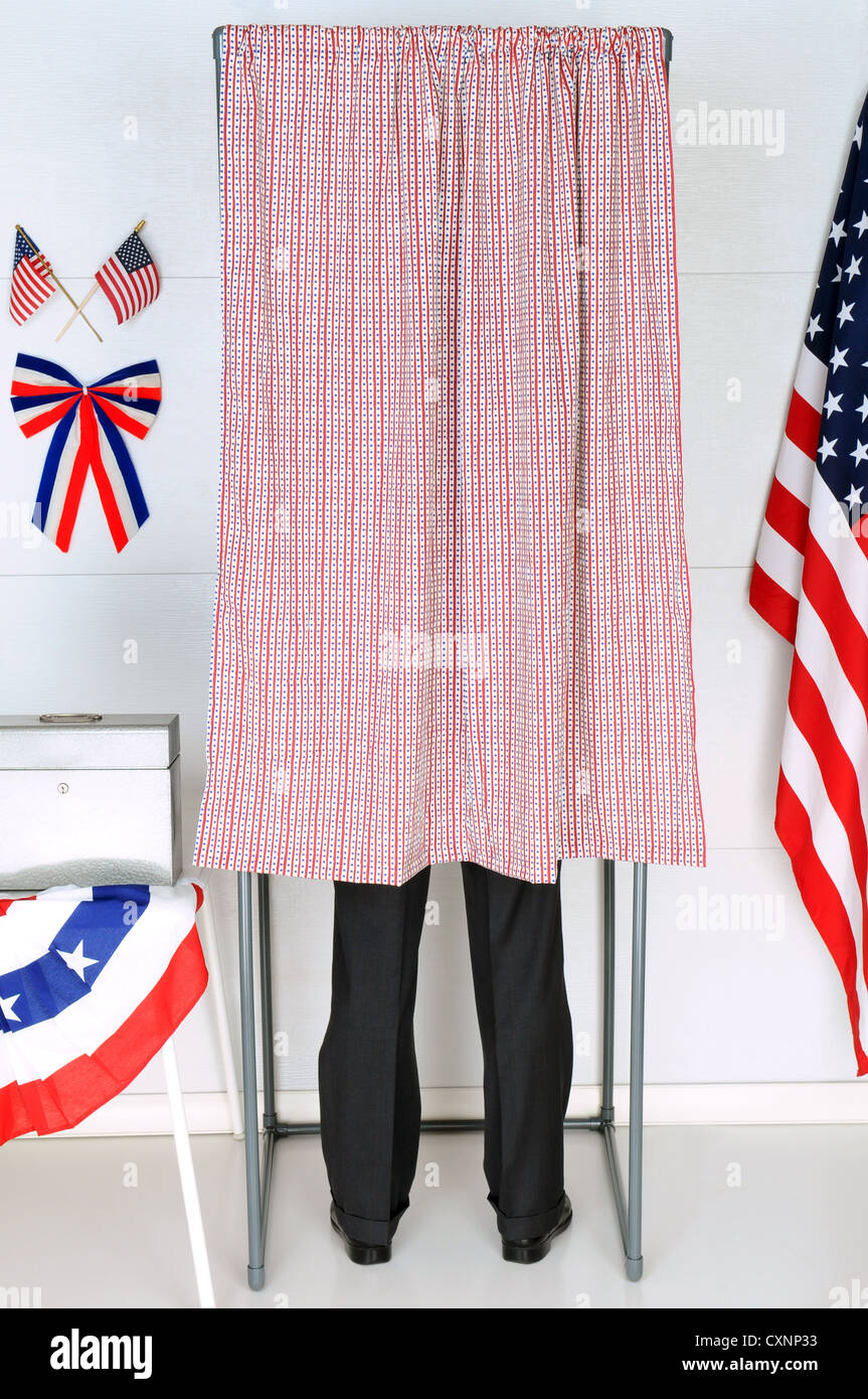 Un homme debout à l'intérieur d'une cabine de vote à son bureau de vote local. Format vertical, l'homme est méconnaissable. Banque D'Images