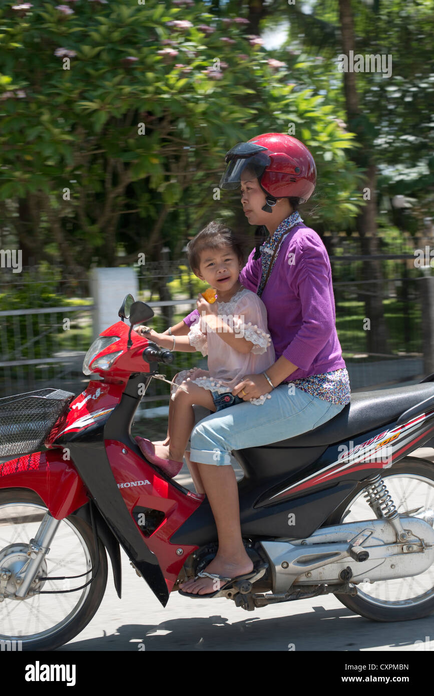 Une mère et son enfant passent sur une moto à Luang Prabang, Laos Banque D'Images