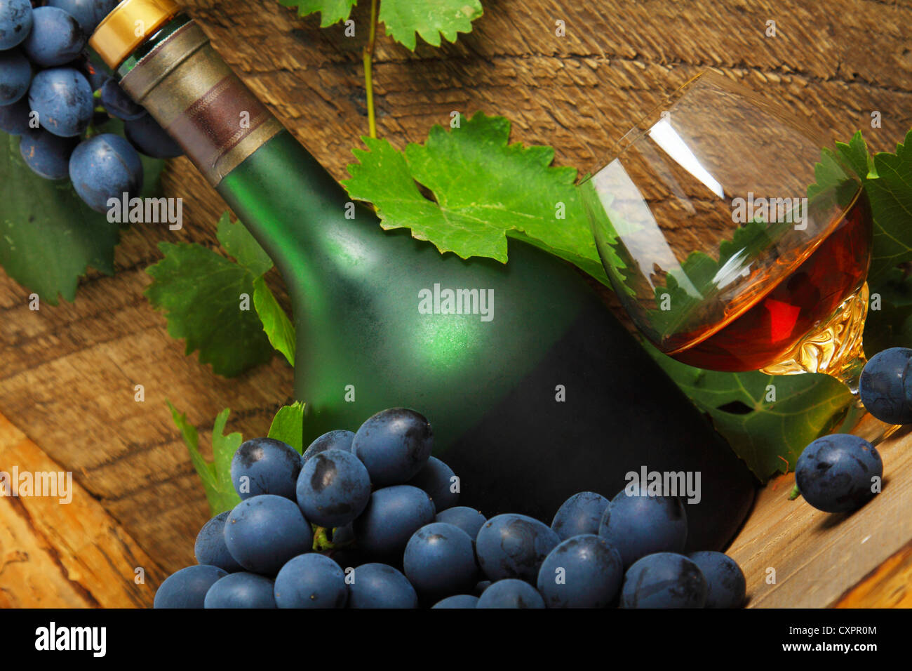 Nature morte avec bouteille, verre de cognac et grappe de raisins Banque D'Images