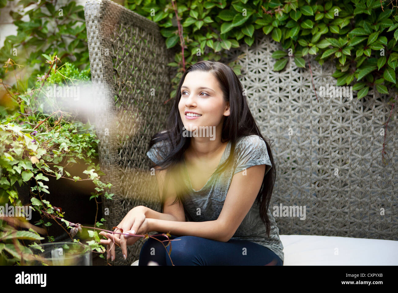 Young woman sitting on bench in garden Banque D'Images