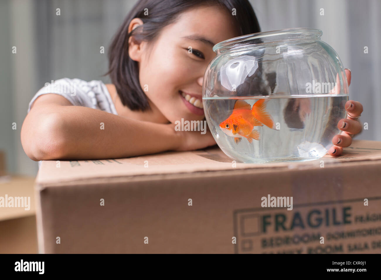 Young woman looking at goldfish sur déménagement fort Banque D'Images