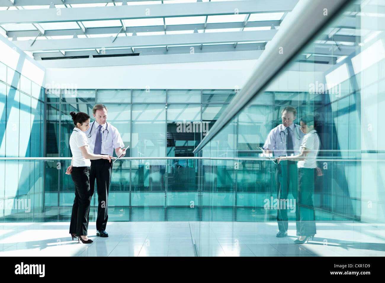 Doctors holding medical records in hospital corridor Banque D'Images