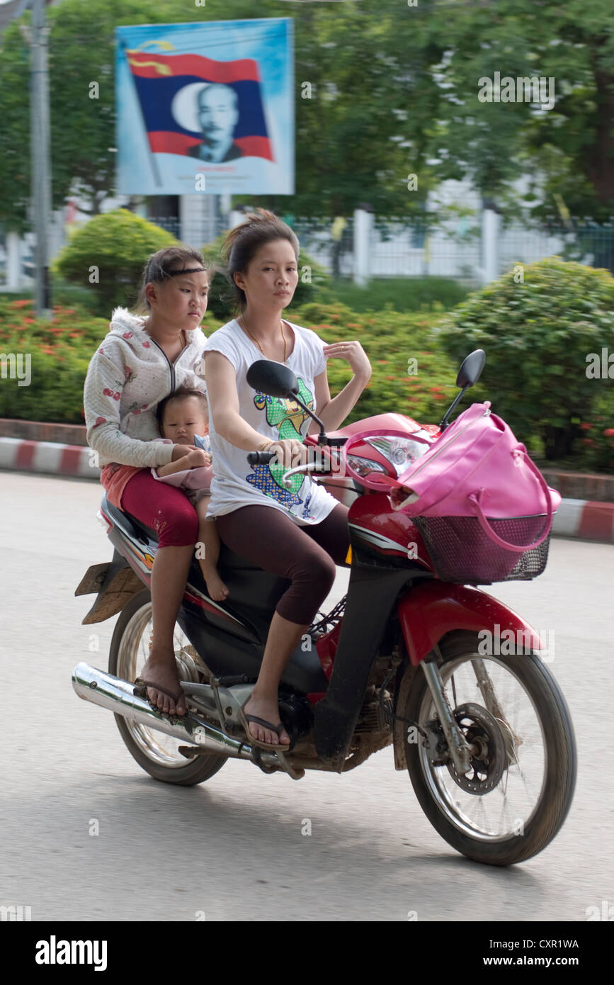 Une jeune mère détient son bébé alors qu'il leurs sur une moto à Luang Prabang, Laos Banque D'Images