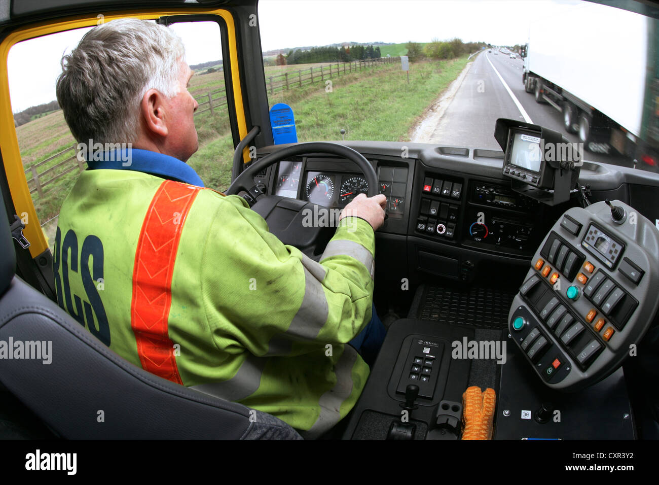 Vue de l'intérieur de l'ouvrier d'entretien de l'autoroute conduisant balayeuse d'autoroute vers le bas Banque D'Images