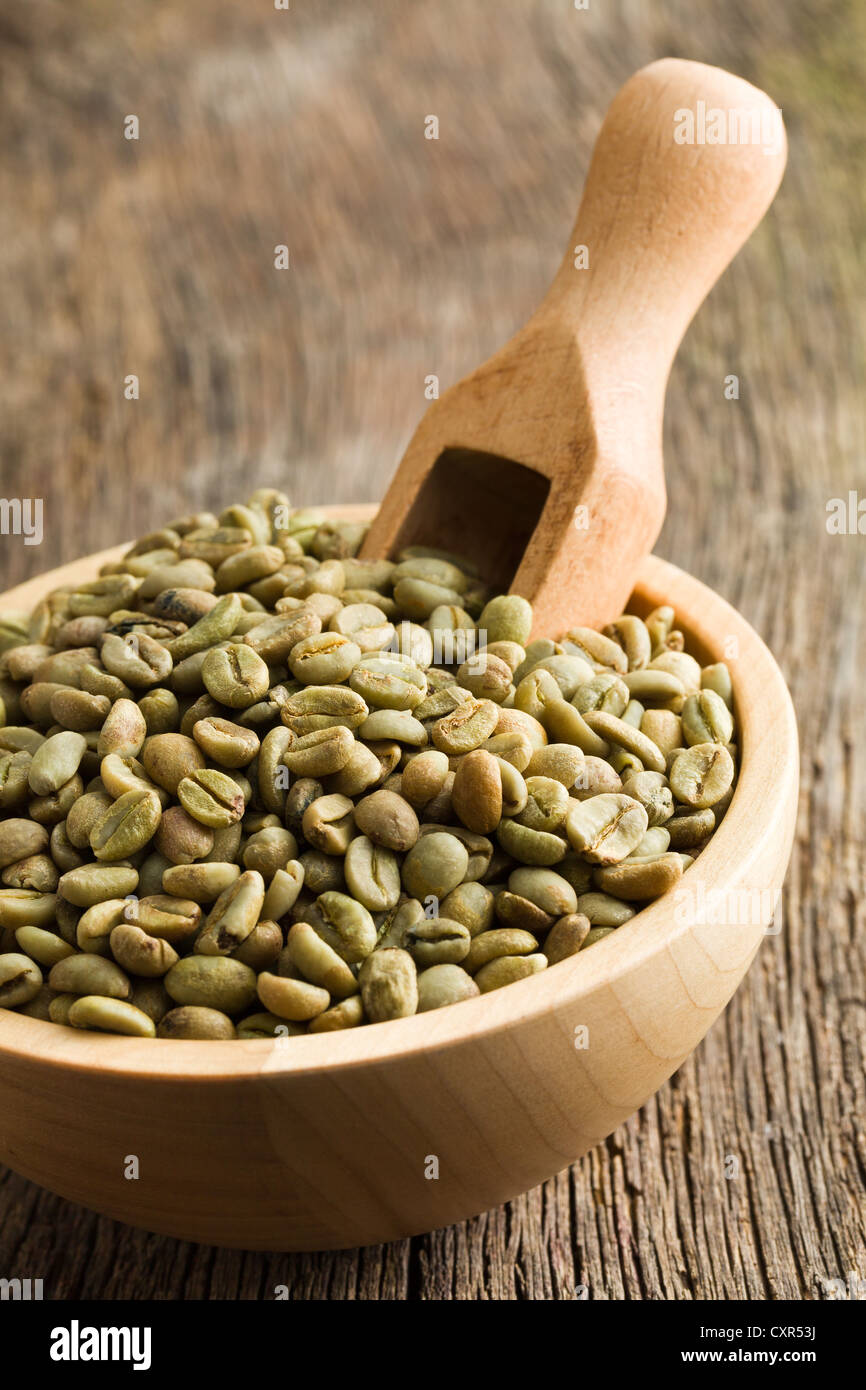 Les grains de café vert avec du scoop dans bol en bois Banque D'Images