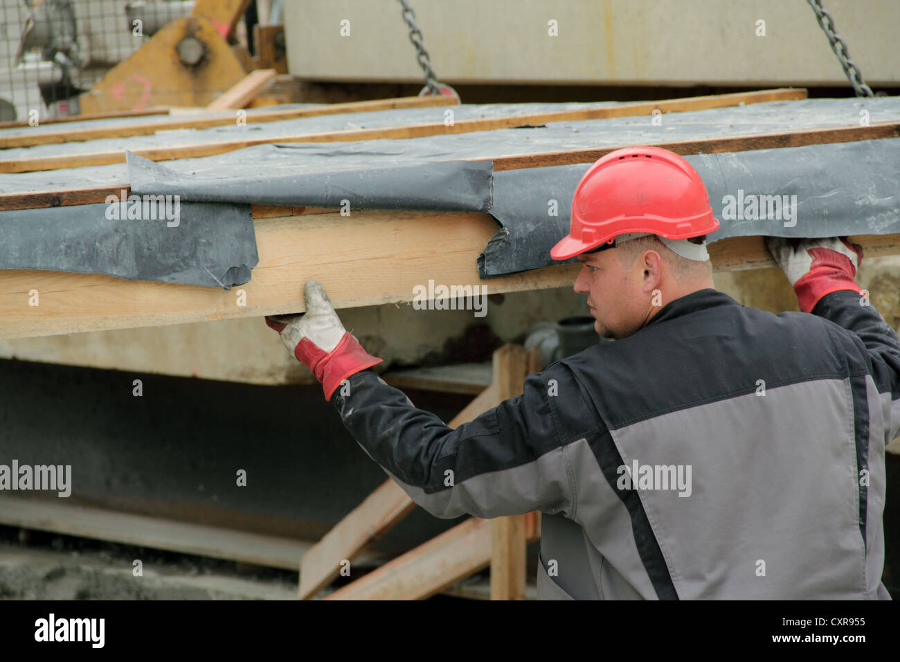 La manipulation d'un travailleur de la construction de bâtiments préfabriqués en bois l'unité étant levé par une grue de construction Banque D'Images