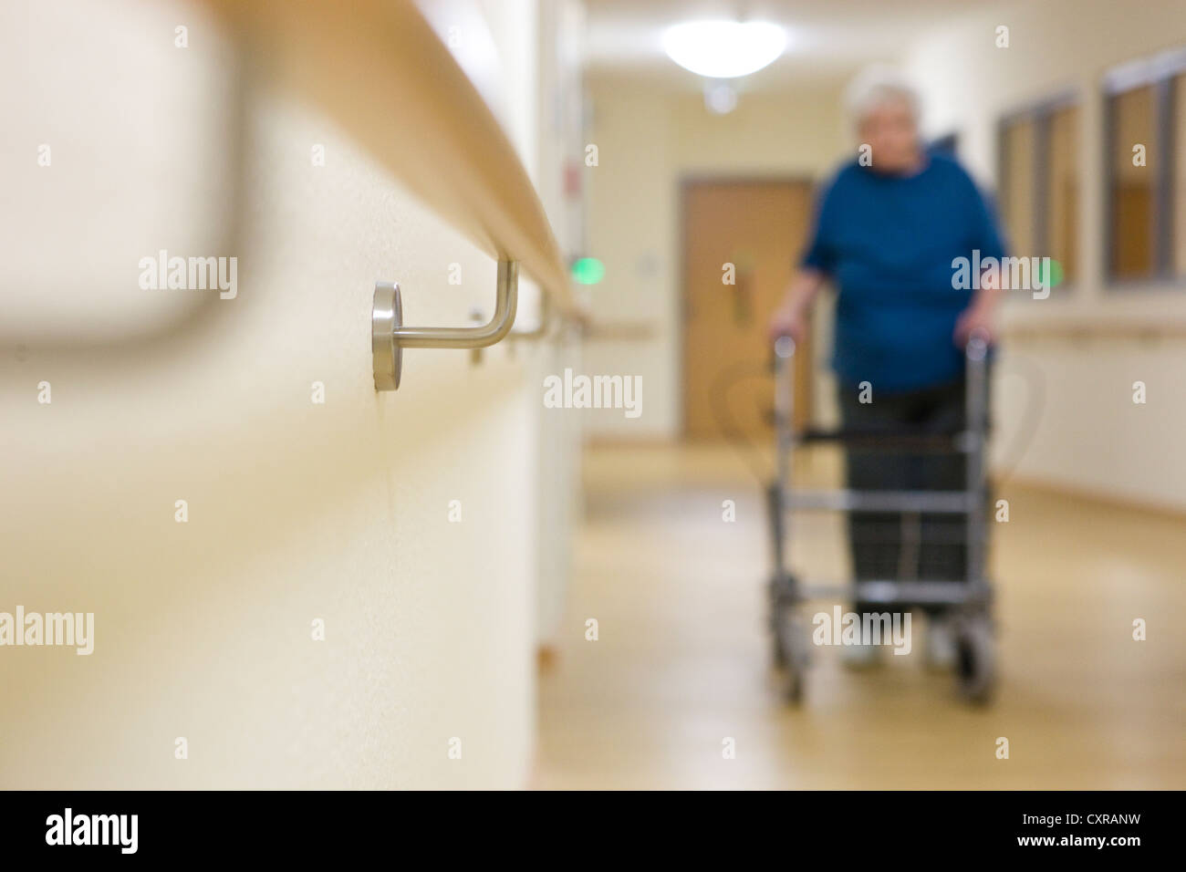 Femme âgée marcher avec un Déambulateur à roues à une maison de soins infirmiers Banque D'Images