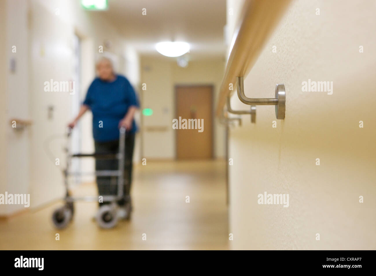 Femme âgée marcher avec un Déambulateur à roues à une maison de soins infirmiers Banque D'Images