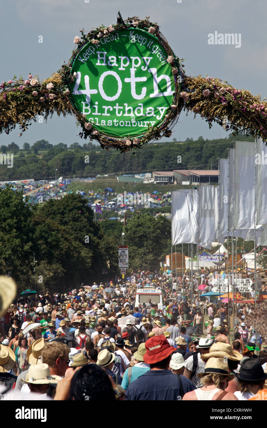 La foule passer sous un heureux 40e anniversaire inscrivez-vous au soleil au festival de Glastonbury Banque D'Images