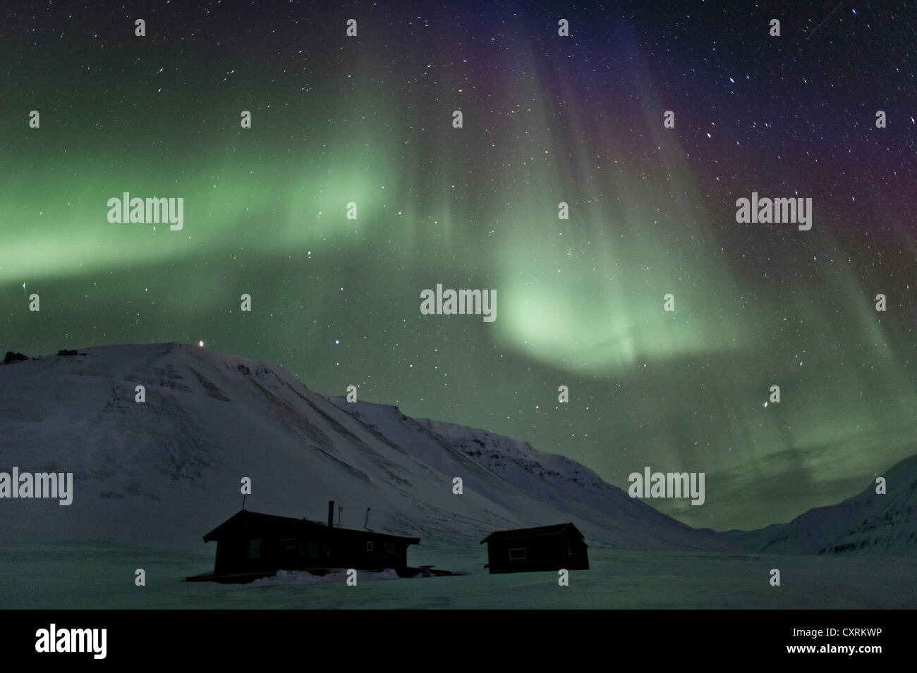 Green Northern Lights, Aurora Borealis, au-dessus de deux petites huttes dans un ciel étoilé, Adventdalen, Todalen, Longyearbyen, Spitsberg Banque D'Images