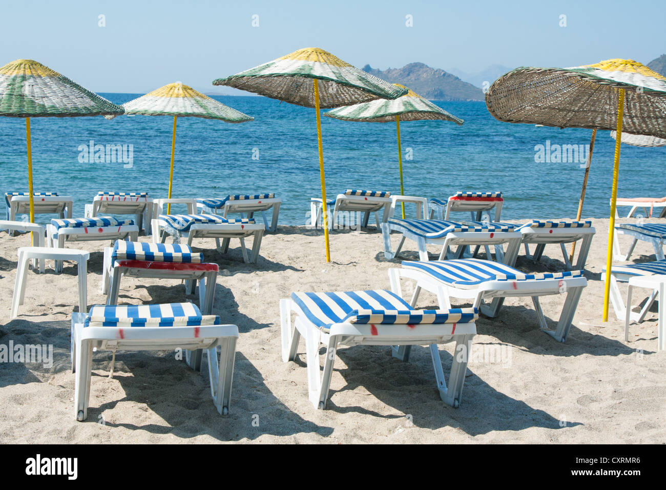 Des chaises longues et des parasols sur la plage de sable d'osier Banque D'Images