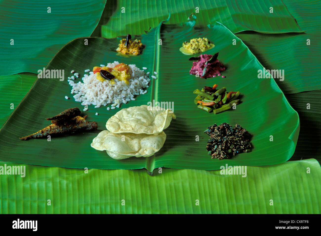 Thali kerala typique avec du riz, le dhal, poisson, légumes et papadam, servi sur une feuille de bananier palm, Kerala, Inde du Sud, Inde Banque D'Images