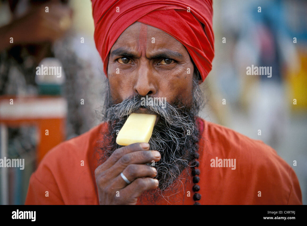 Sadhu avec un turban rouge manger une glace, Kashi, Varanasi ou Benares, Uttar Pradesh, Inde du Nord, Inde, Asie Banque D'Images