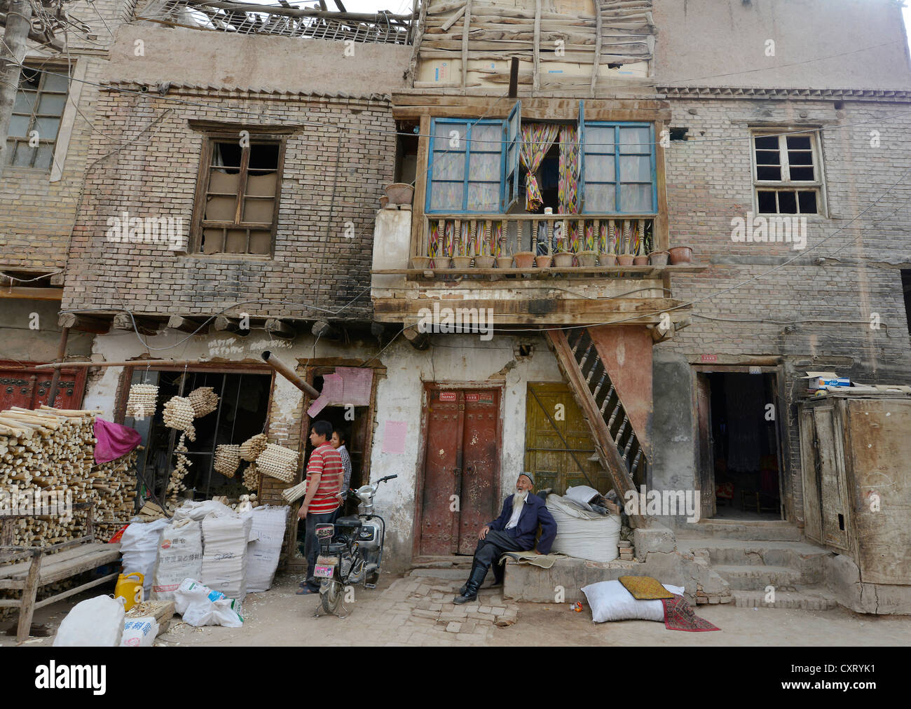 Ancien musulman avec une barbe et deux jeunes travailleurs du bois dans une vieille maison de terre séchée et les Ouigours, artisan street, Kashgar Banque D'Images