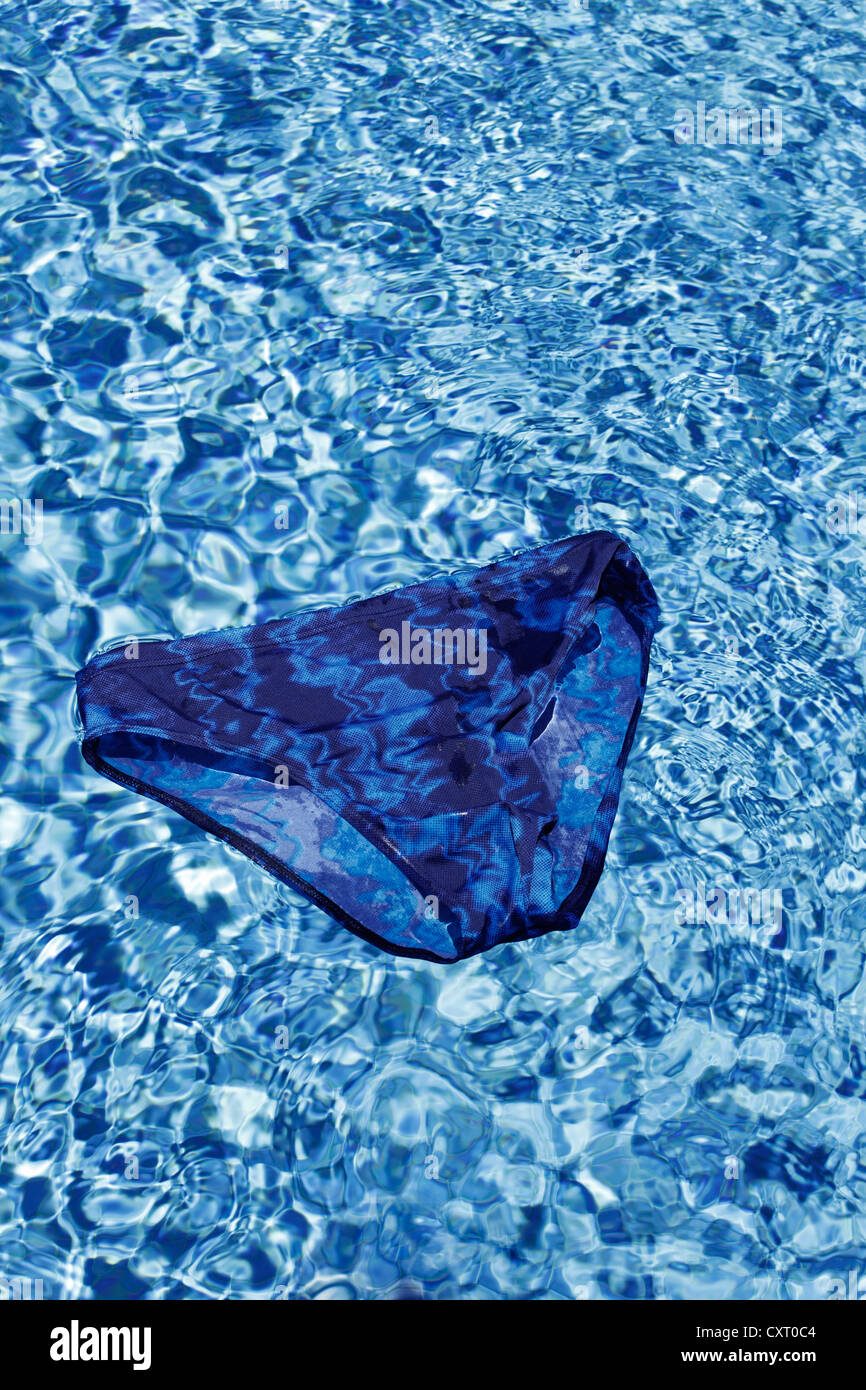 Maillot de bain bleu flottant à la surface d'une piscine extérieure, d'image symbolique pour les vacances ou les jours fériés Banque D'Images
