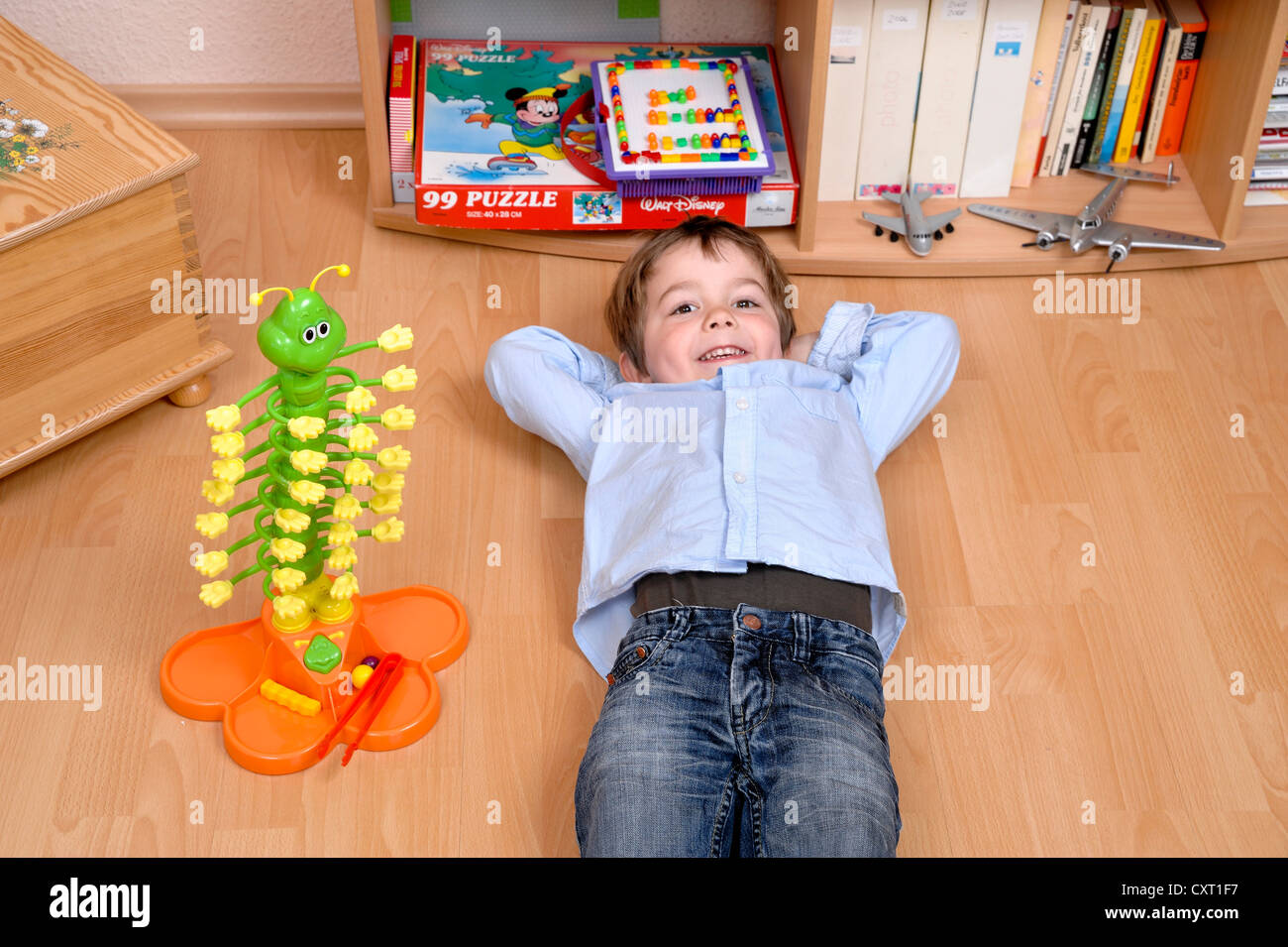 Garçon, 4, allongé sur le sol, à côté d'un jeu de billes Banque D'Images