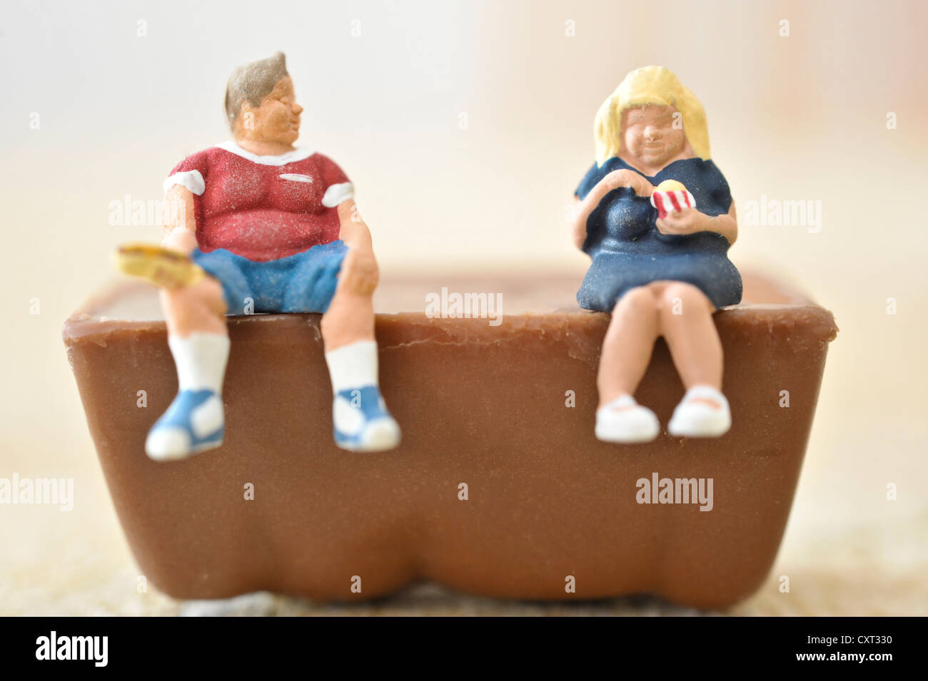 Chiffres obèses miniature assis un morceau de chocolat Banque D'Images