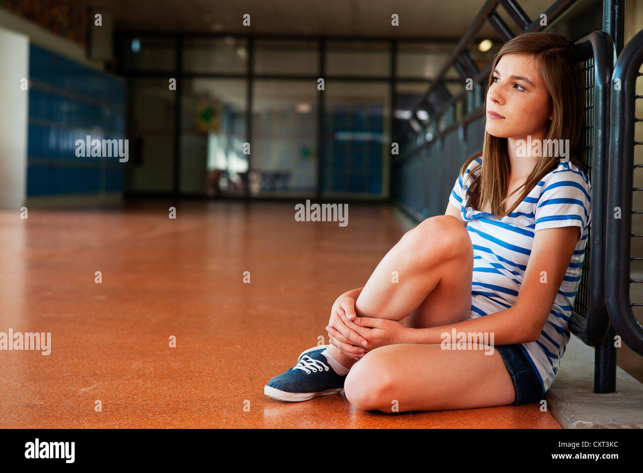 Lycéenne assise seule dans le bâtiment de l'école, appuyée contre une balustrade Banque D'Images