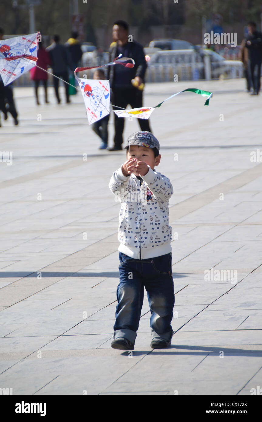 Jeune garçon chinois jouant avec un cerf-volant, la place Tiananmen, à Beijing Banque D'Images