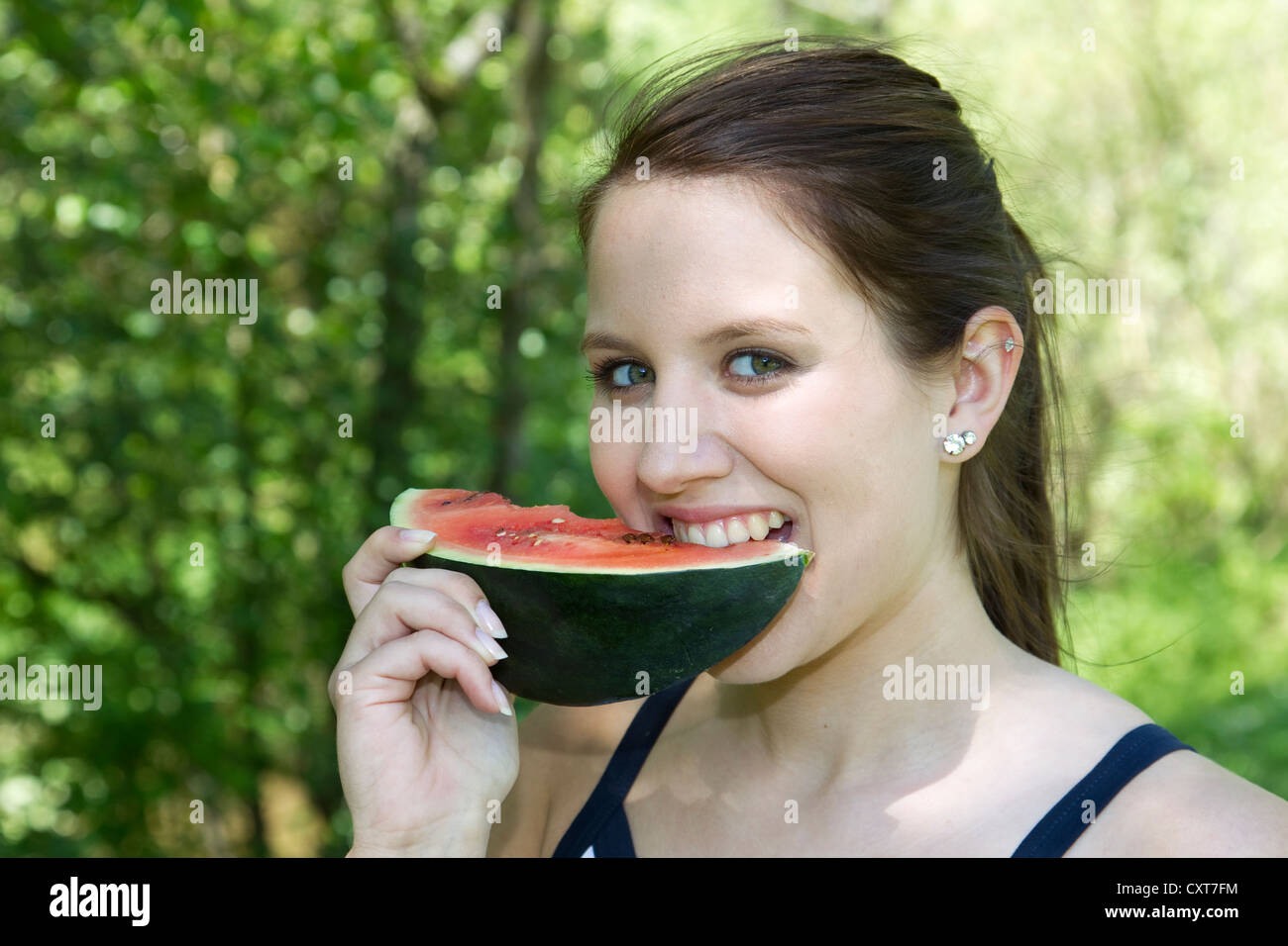 Jeune femme mordre dans un morceau de pastèque Banque D'Images