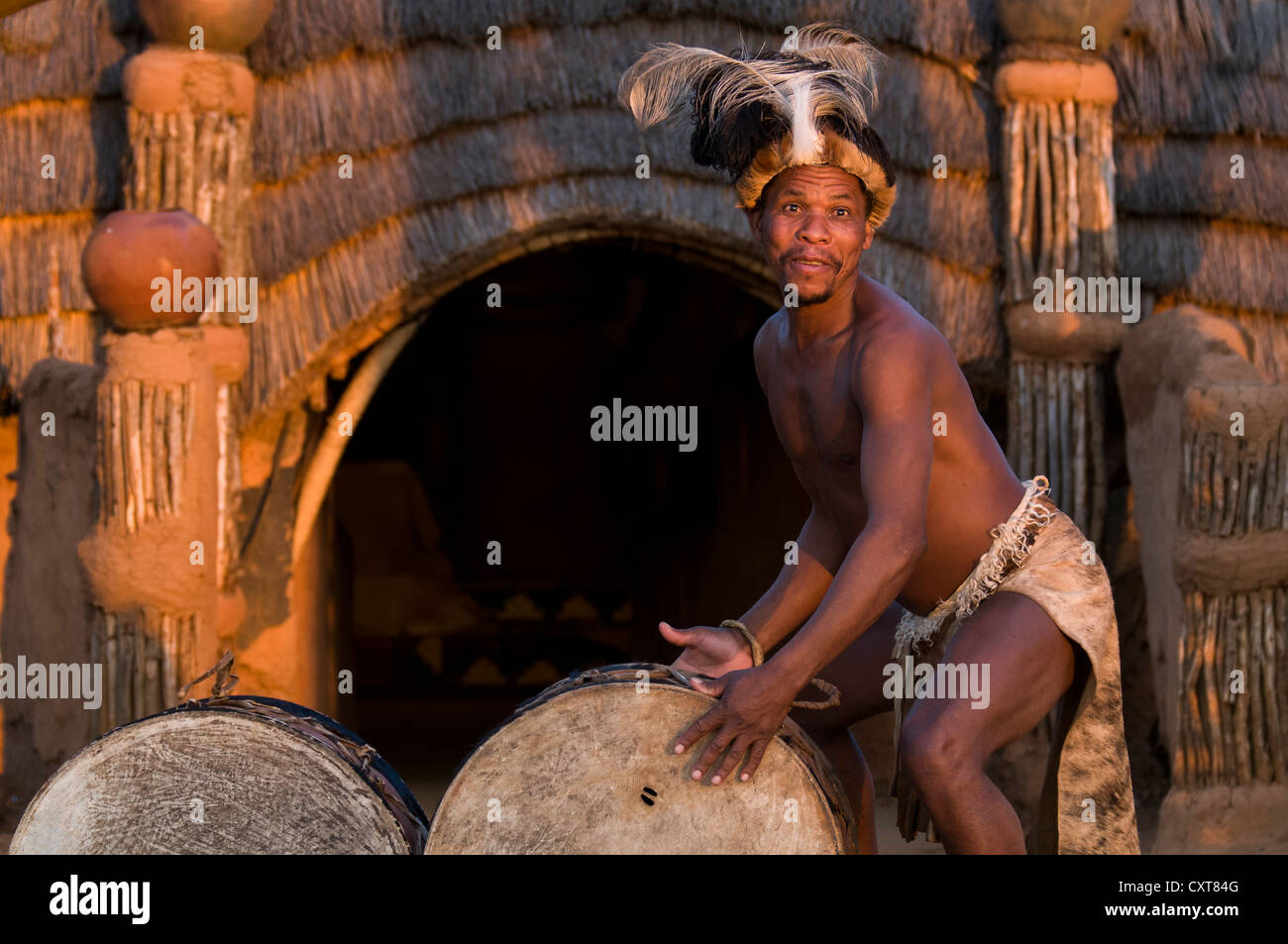 Zulu homme en costume traditionnel à jouer de la batterie, l'ensemble de film Shakazulu, Shakaland, KwaZulu-Natal, Afrique du Sud, l'Afrique Banque D'Images
