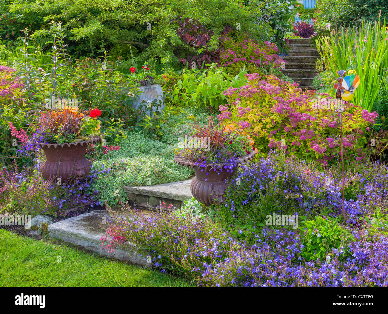 Vashon Island, WA : urnes en pot sur l'entrée de l'escalier en pierre avec jardin de plantes vivaces d'été Banque D'Images